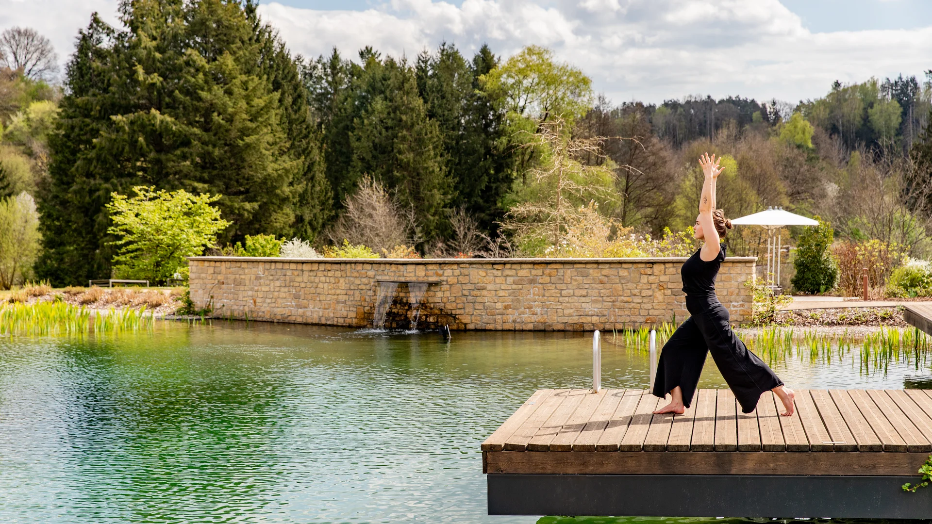 Pressebilder Frau macht Yoga auf Holzsteg über natürlichen Teich in Waldumgebung