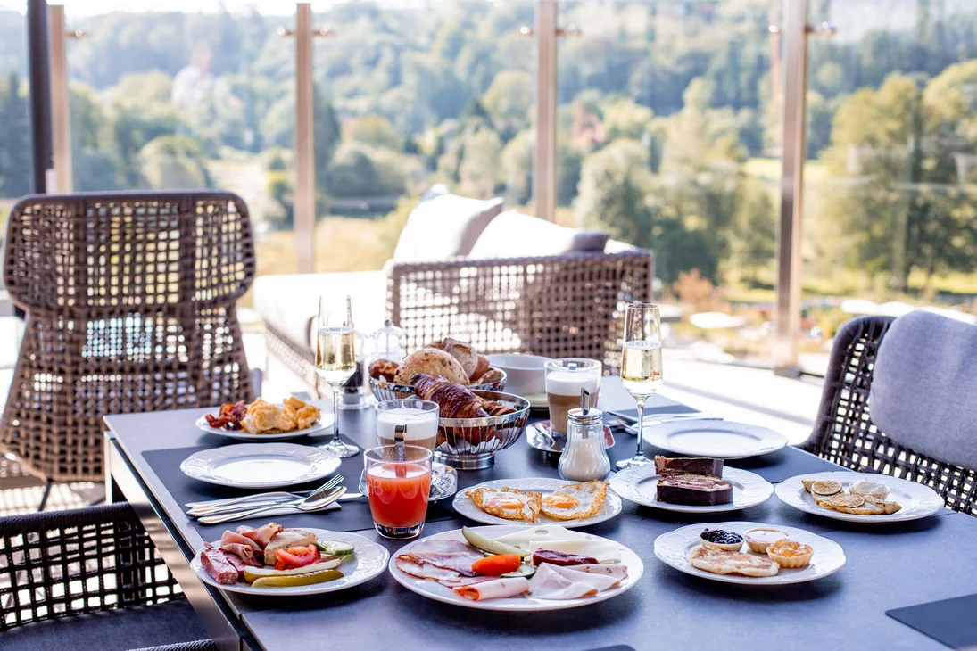Frühstückstisch mit Eiern, Aufschnitt, Croissants und Getränken auf Terrasse