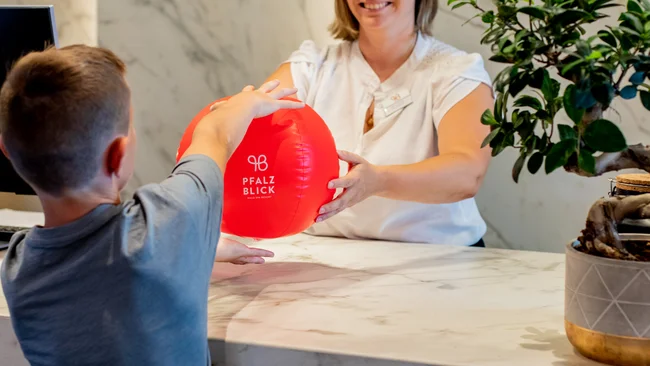 Kind bekommt roten Ball an einer modernen Rezeption übergeben