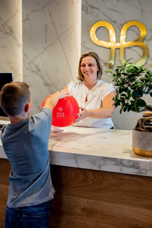 Kind bekommt roten Ball an einer modernen Rezeption übergeben