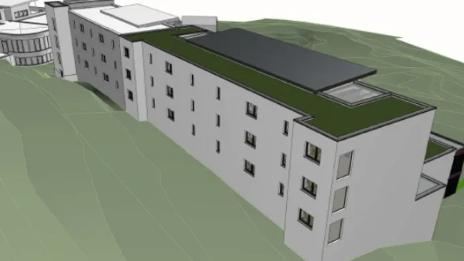 Mehr Komfort für besondere Urlaubsmomente Architekturmodell eines langen weißen Gebäudes mit begrüntem Dach und dunkler Dachfläche