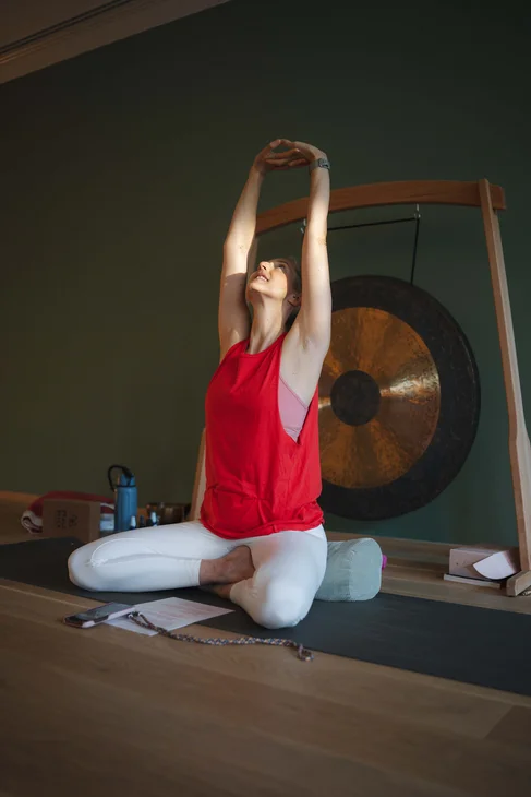 Frau praktiziert Yoga in rotem Top vor einer großen Klangschale