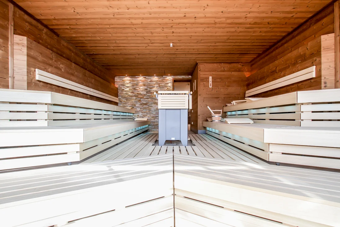 Vapeur, senteur, bonheur : sauna sensorielavec vue naturelle Sauna en bois moderne avec bancs clairs et mur en pierre en arrière-plan