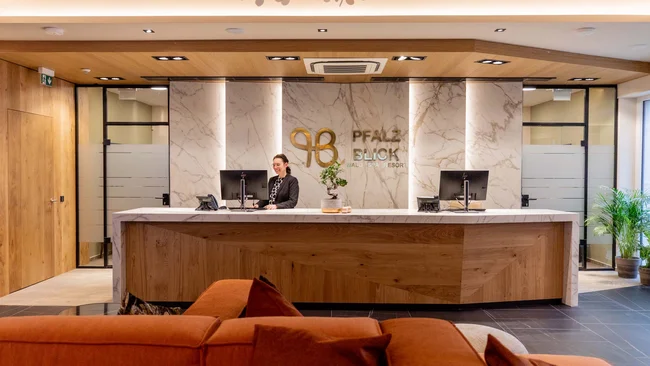 Empfangstresen mit Angestellter in modernem Hotel mit Holz- und Marmordesign