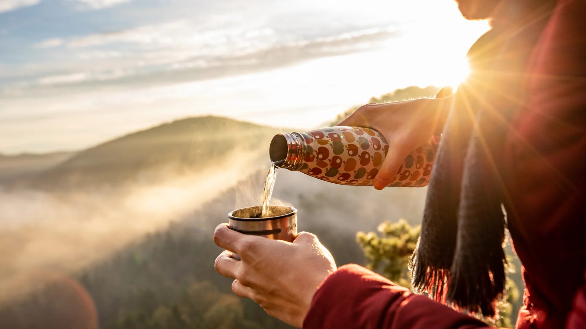 Randonnée dans le Palatinat avec hébergement Personne versant du thé chaud d'une bouteille thermos dans une tasse au coucher du soleil