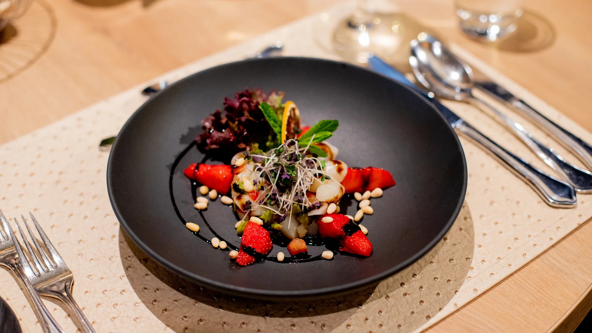 Ihr Hotel im Dahner Felsenland: Pfalzblick Wald Spa Resort Gourmet-Salat mit Erdbeeren, Nüssen und frischen Kräutern auf schwarzem Teller