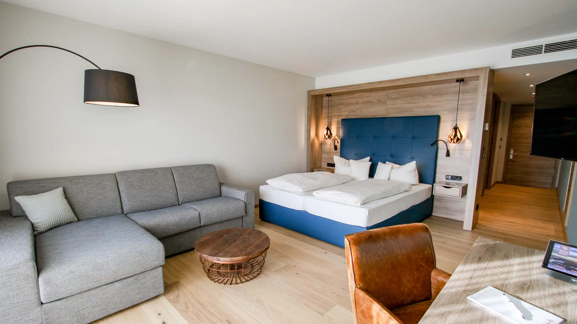 Moderne Hotelzimmer mit Bett, Sofa, Schreibtisch und Holzfußboden