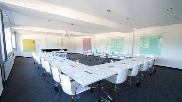 Moderner Konferenzraum mit weißen Stühlen und Tischen in U-Form