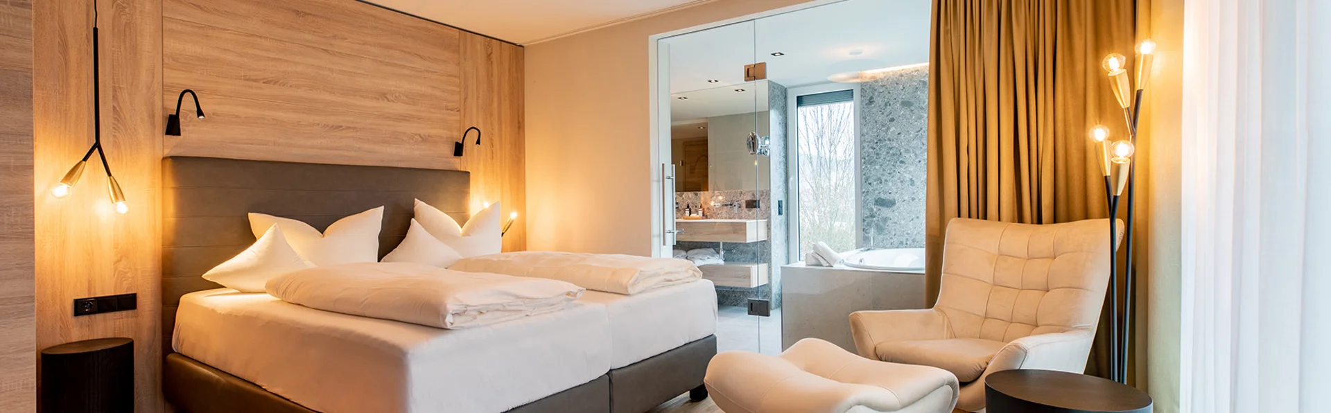 Erholsamer Schlaf im Urlaub - Wellness und Ruhe im Pfalzblick Wald Spa Resort Modernes Hotelzimmer mit Doppelbett und offener Badewanne mit Glaswand