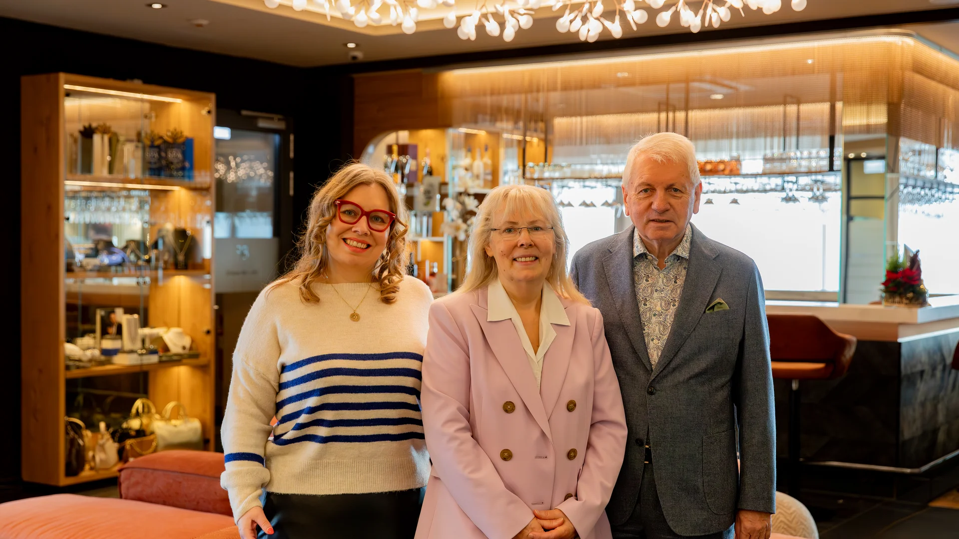 Drei lächelnde Personen in stilvollem Raum mit moderner Beleuchtung