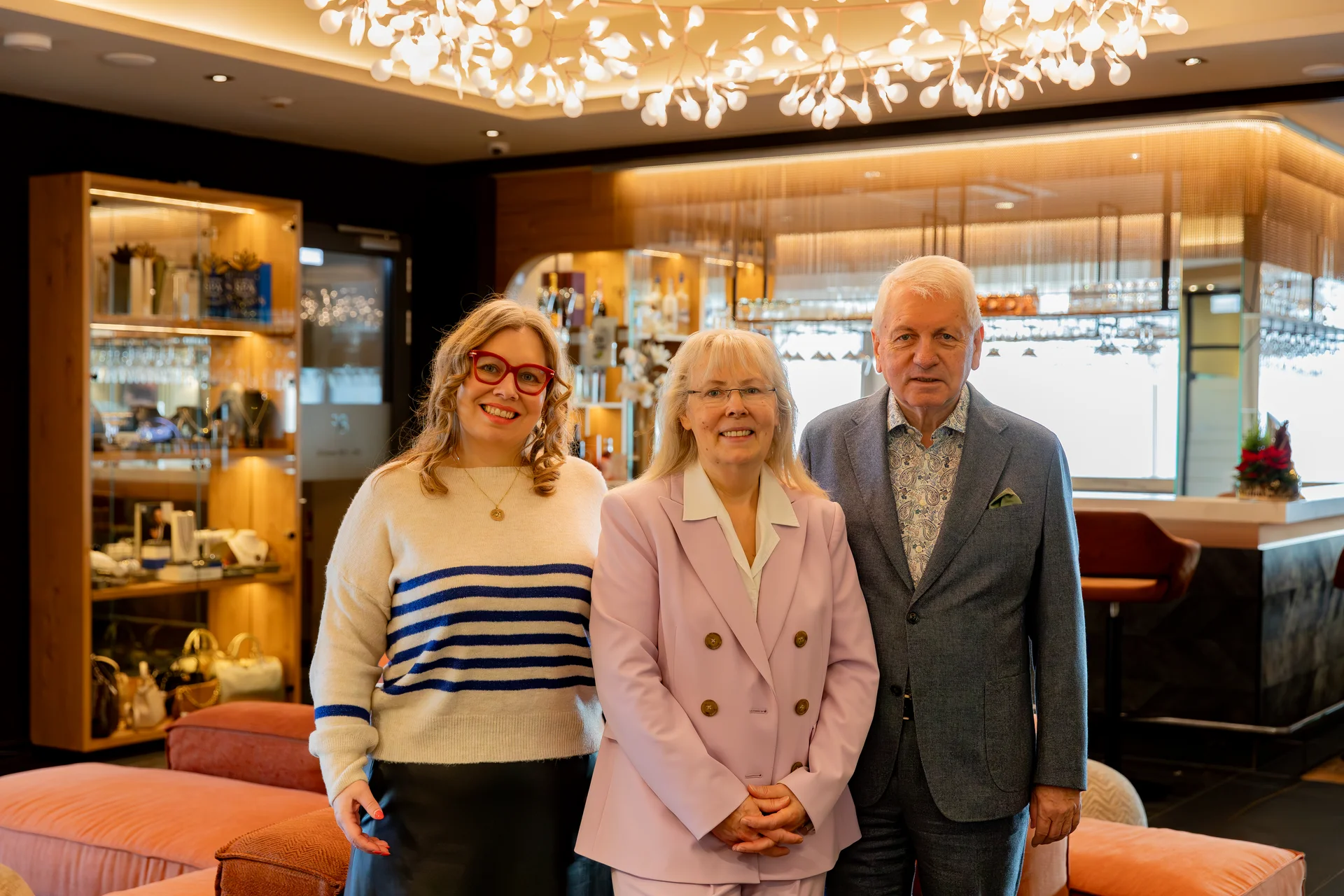 Three smiling people in a stylish room with modern lighting