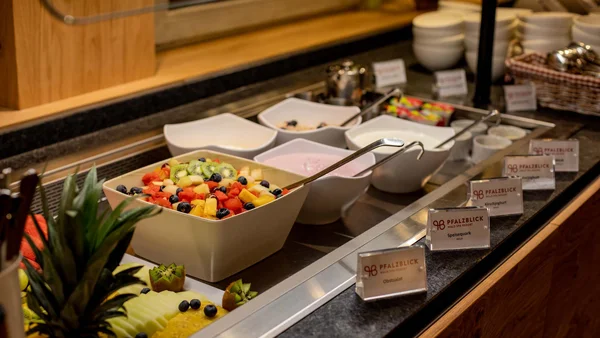Buffet mit frischem Obstsalat, Joghurt und Quark in weißen Schalen