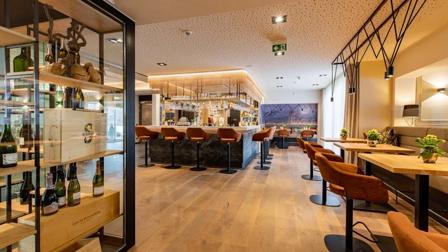 Moderner Hotelbarbereich mit Holzfußboden und orangefarbenen Barhockern