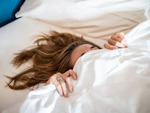 Ihr Hotel im Dahner Felsenland: Pfalzblick Wald Spa Resort Person liegt im Bett und zieht sich mit den Händen an der Decke fest