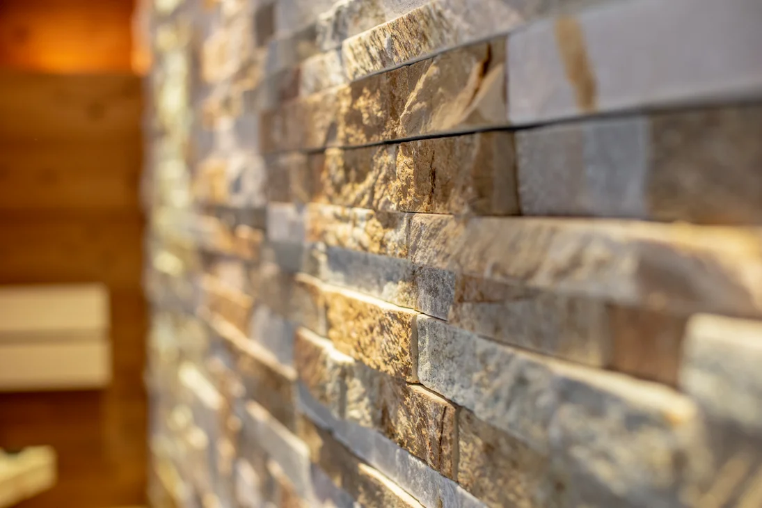 Vapeur, senteur, bonheur : sauna sensorielavec vue naturelle Gros plan sur un mur revêtu de pierre éclairé par une lumière chaude
