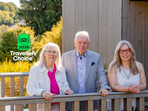 Ihr Hotel im Dahner Felsenland: Pfalzblick Wald Spa Resort Drei ältere Personen stehen auf einer Holzbrücke vor grüner Landschaft