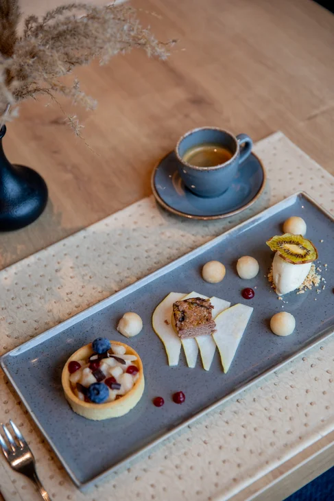 Feines Dessert mit Beeren, Käsekuchen und Espresso auf grauem Teller