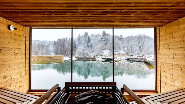 Innensauna mit Holzwänden und Blick auf verschneite Landschaft und See