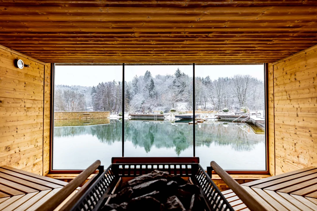 Innensauna mit Holzwänden und Blick auf verschneite Landschaft und See