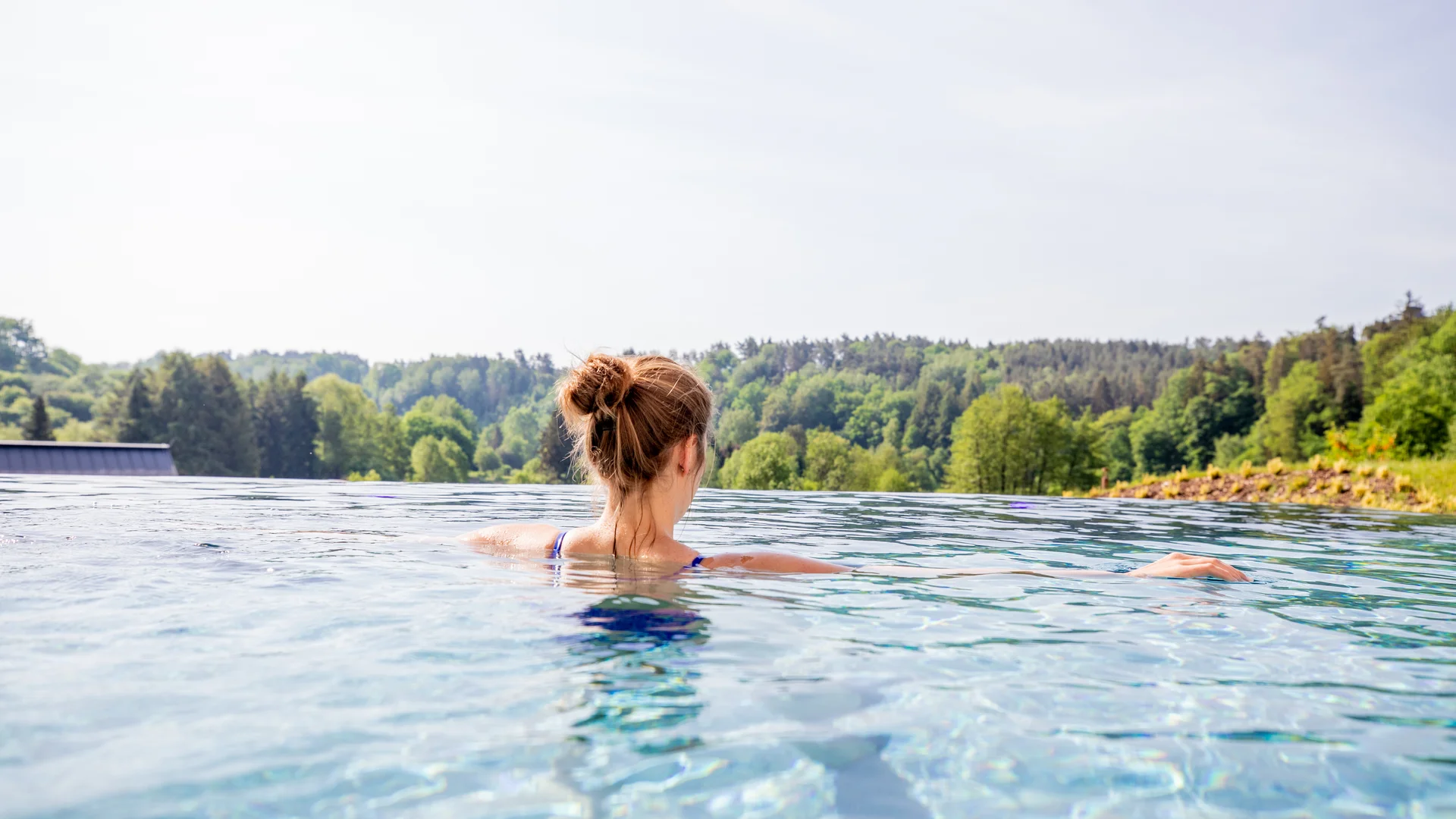 Pressebilder Frau entspannt im Infinity-Pool mit Blick auf einen Wald