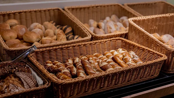 Verschiedene Brotsorten in Weidenkörben auf einem Holztisch
