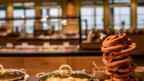 Gestapelte Brezeln neben bedeckten Töpfen in einem Buffetrestaurant