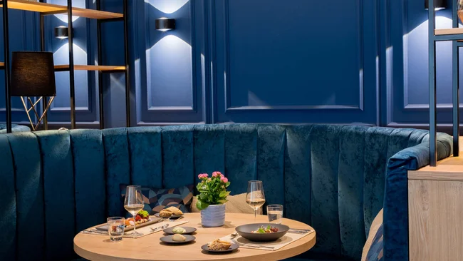 Elegante Sitzecke mit rundem Holztisch und blauen Polstern im Restaurant