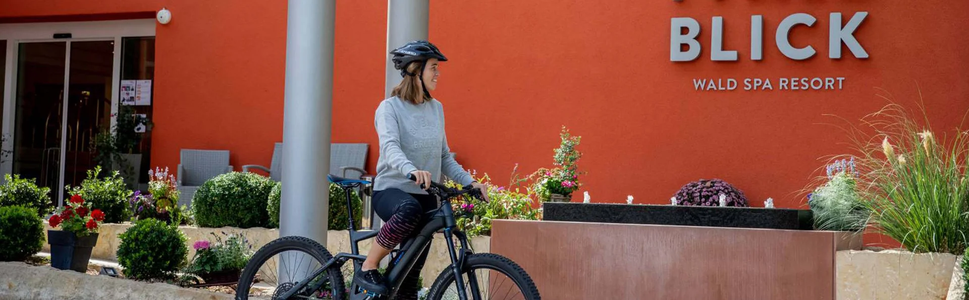Frau mit Helm auf Fahrrad vor Pfalz Blick Wald Spa Resort