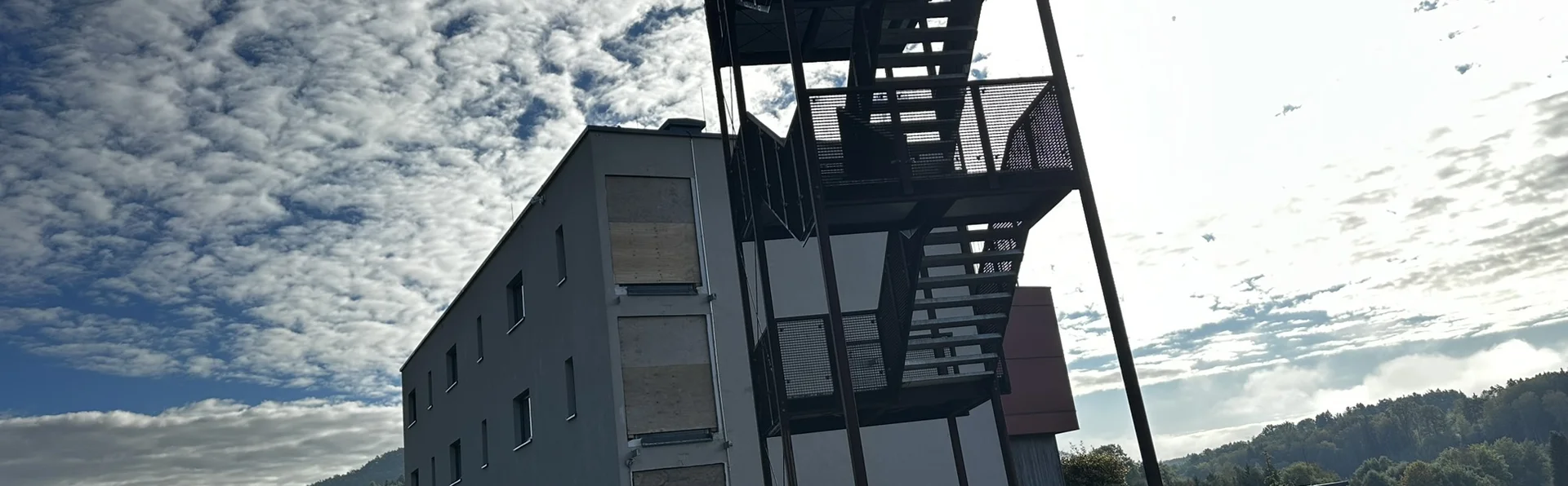 Des ouvriers guident un grand escalier métallique suspendu près d’un bâtiment moderne