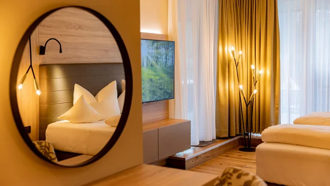 Modernes Hotelzimmer mit Badspiegel, gemütlichem Bett und warmem Licht