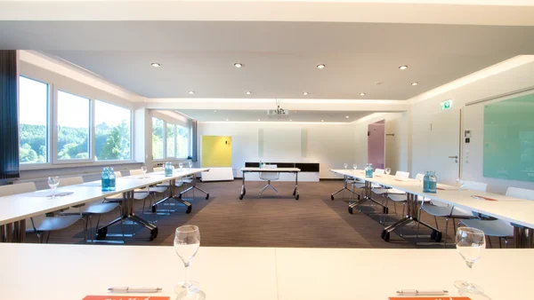 Moderner Konferenzraum mit Tischen, Stühlen und großer Fensterfront