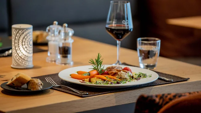 Elegantes Restauranttischgericht mit Gemüse, Salz und Pfeffer, Rotwein und Kerze