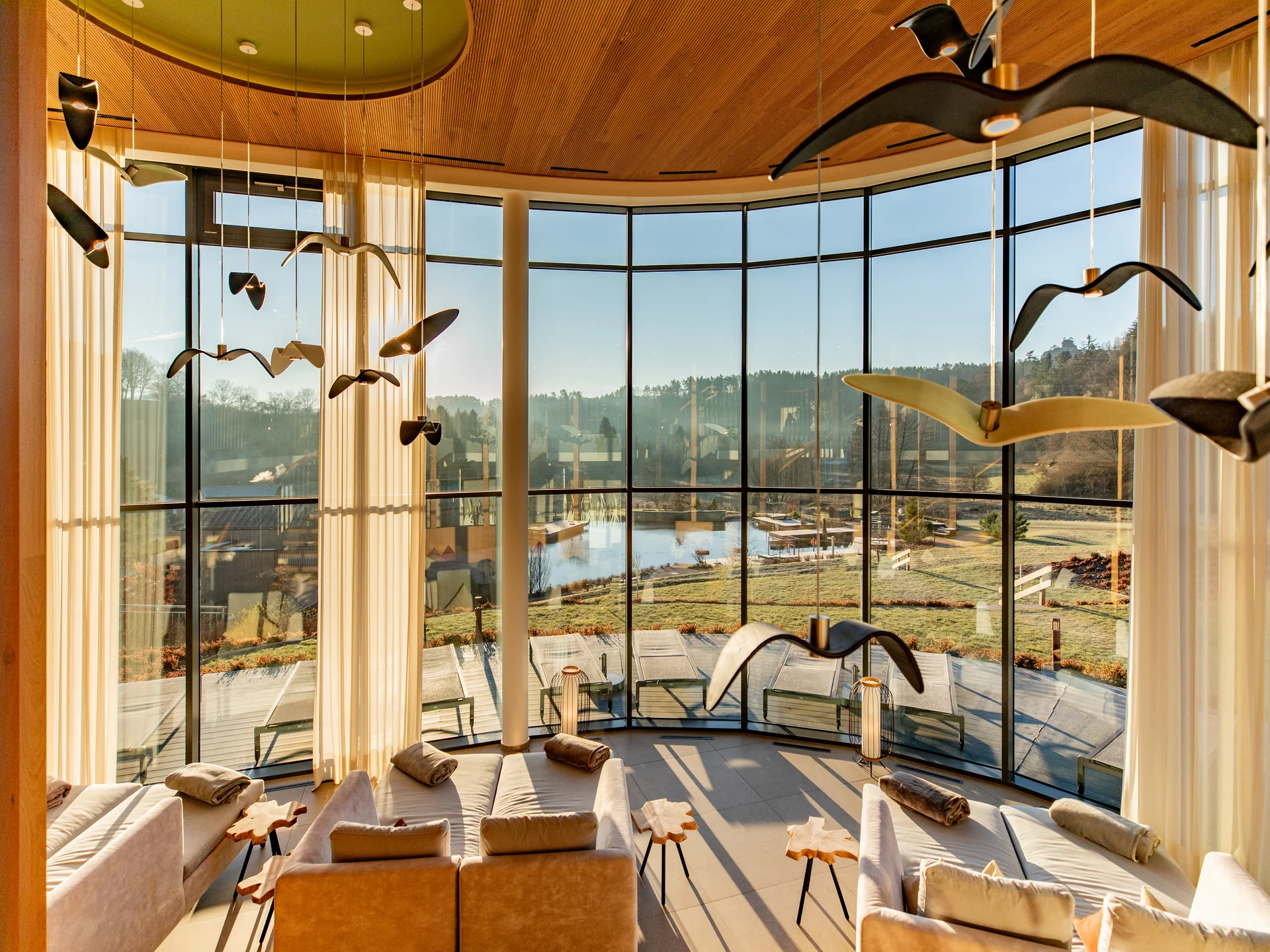 Wohnzimmer mit großen Fensterfronten und Vogel-Deckendekoration