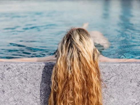 Blog – Neuigkeiten aus dem Pfalzblick Wald Spa Resort Frau mit langen, nassen Haaren lehnt am Poolrand