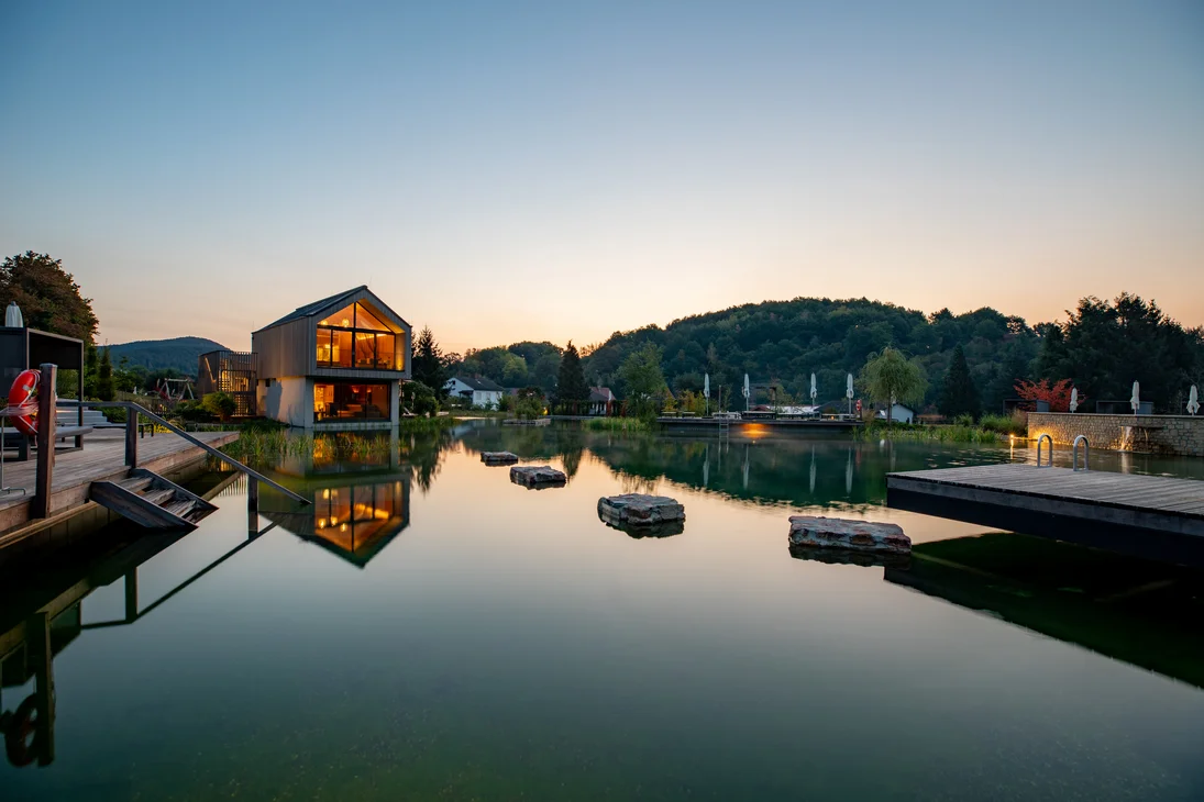 Vapeur, senteur, bonheur : sauna sensorielavec vue naturelle Maison moderne au bord d'un lac calme avec pierres et quai au coucher du soleil