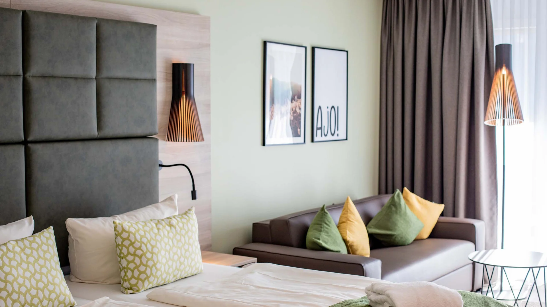Modernes Hotelzimmer mit Bett, Sofa und dekorativen Kissen