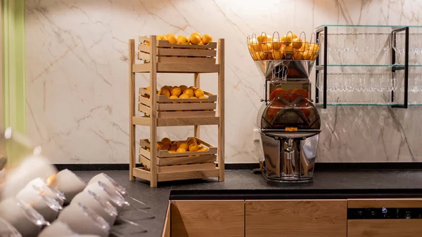 Küche mit Orangen in Holzkisten und Entsafter auf der Arbeitsplatte