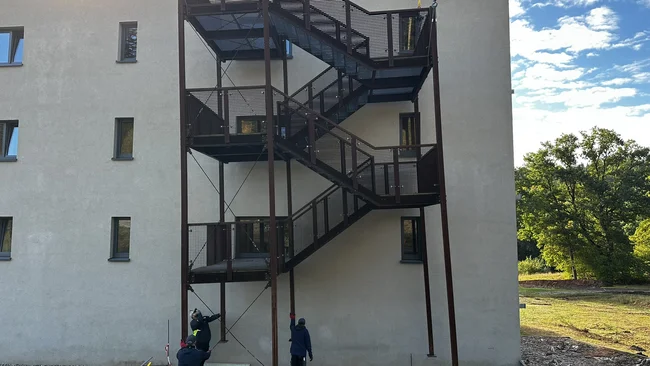 Des ouvriers installent un escalier extérieur à plusieurs niveaux sur un bâtiment