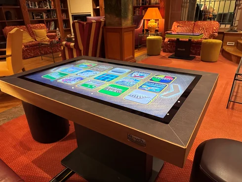 Interaktiver Spieltisch mit digitalen Spielen in gemütlicher Bibliothek