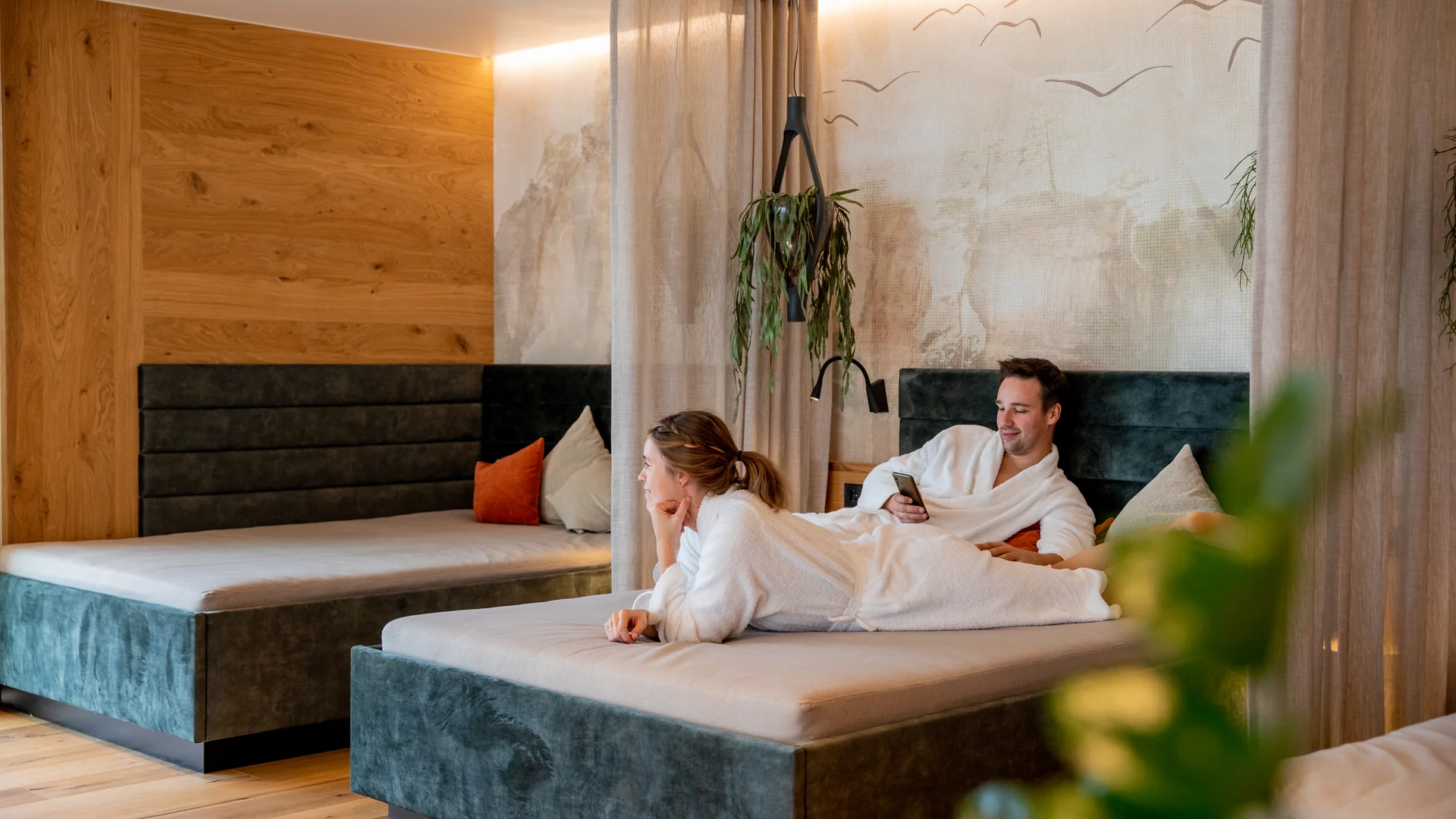 Pressebilder Paar in Bademänteln entspannt sich auf Betten in gemütlichem Raum