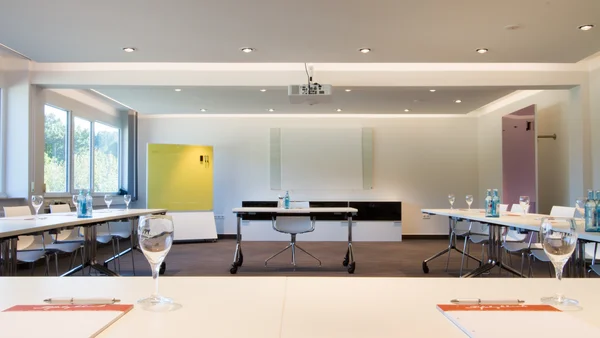 Konferenzraum mit Tischen, Stühlen, Gläsern und Projektor an der Decke