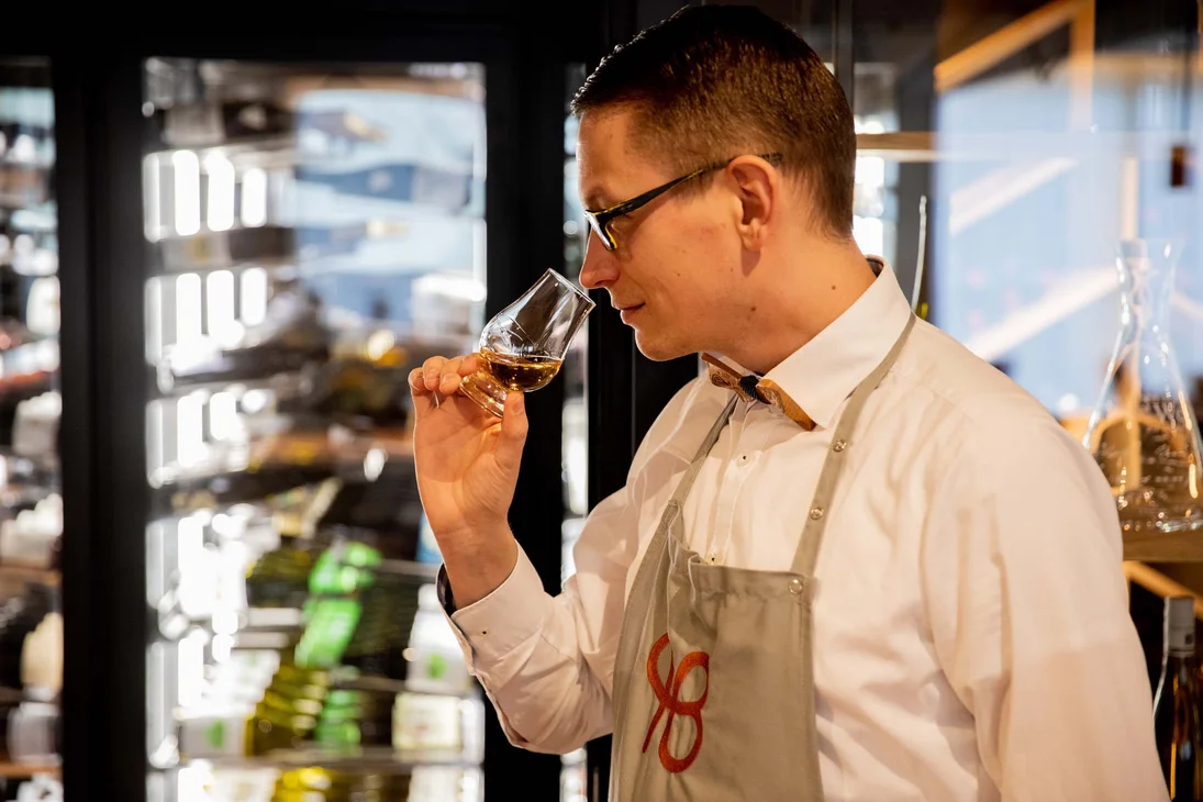 Mann riecht an einem Glas mit Whisky in einem Geschäft