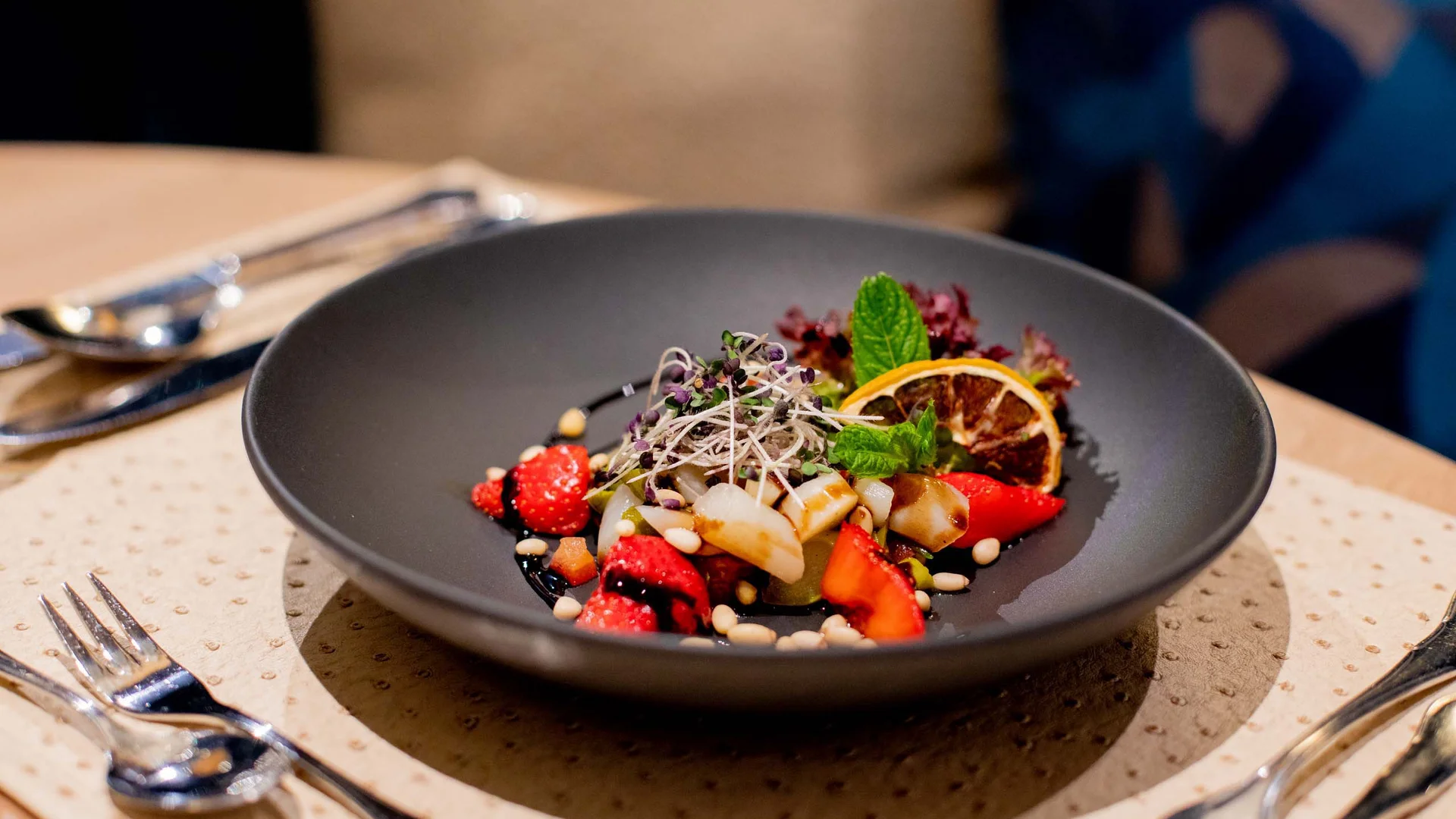 Salade artistiquement dressée avec fraises, graines et herbes dans un bol noir