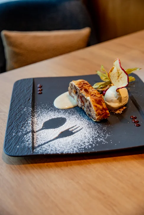 Blech mit Apfelstrudel, Vanilleeis und Dekoration aus Puderzucker auf Holztisch