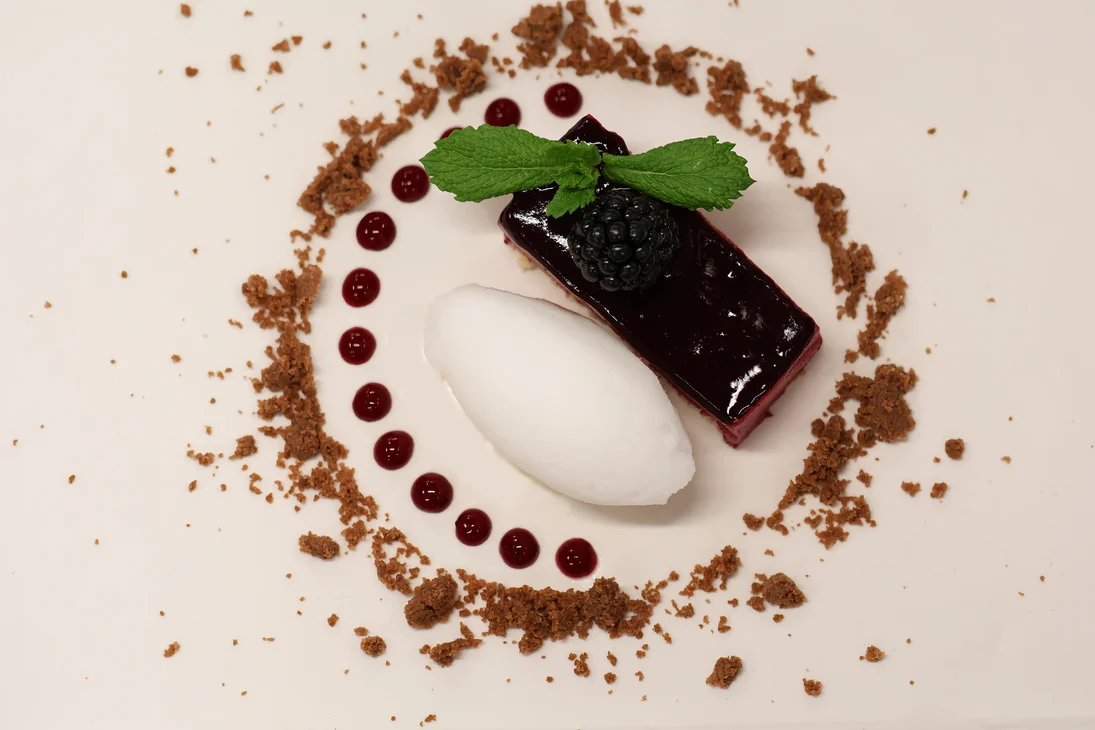 Elegantes Dessert mit Beerenmousse, Eiscreme, Minzblatt und Schokostreuseln