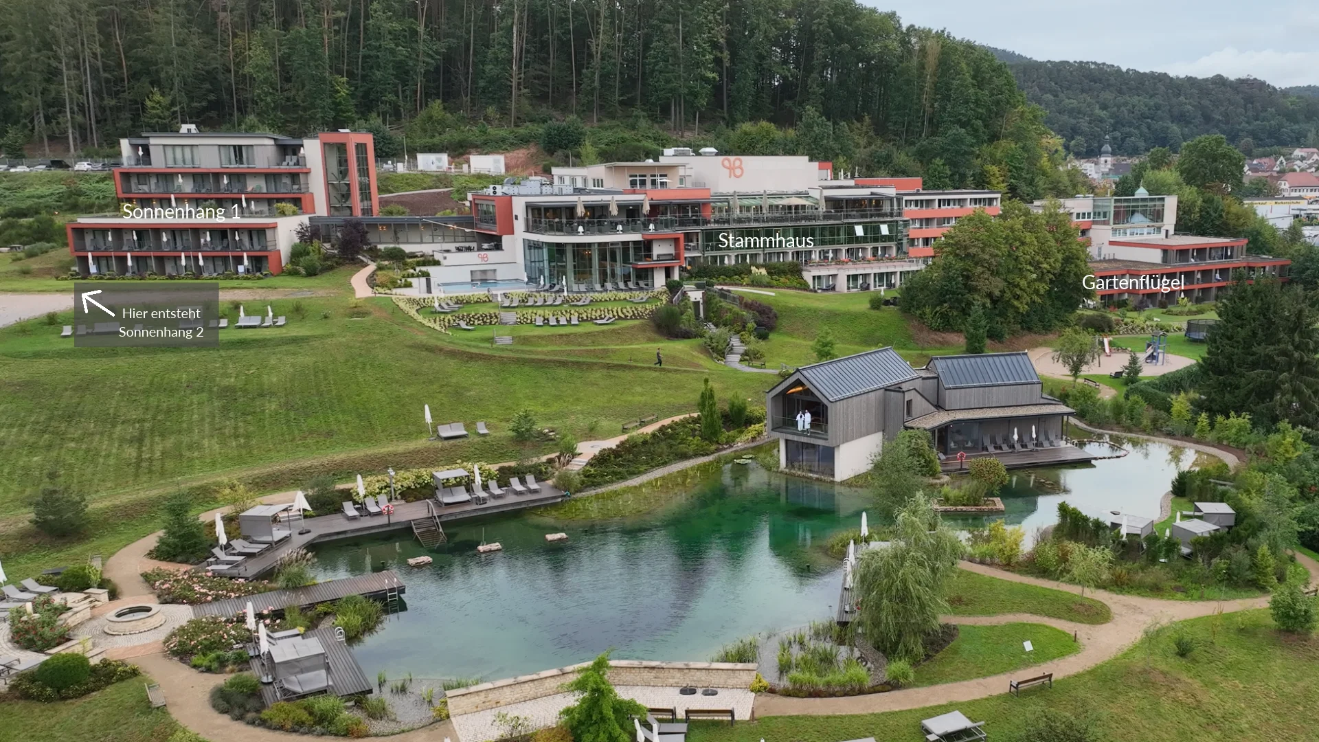 Vue aérienne d’un complexe hôtelier moderne avec un étang, des jardins et une forêt