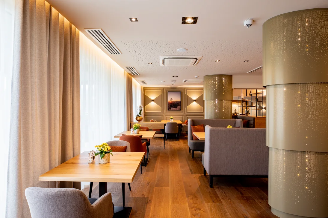 Modernes Café mit Holztischen, bequemen Stühlen und warmem Licht