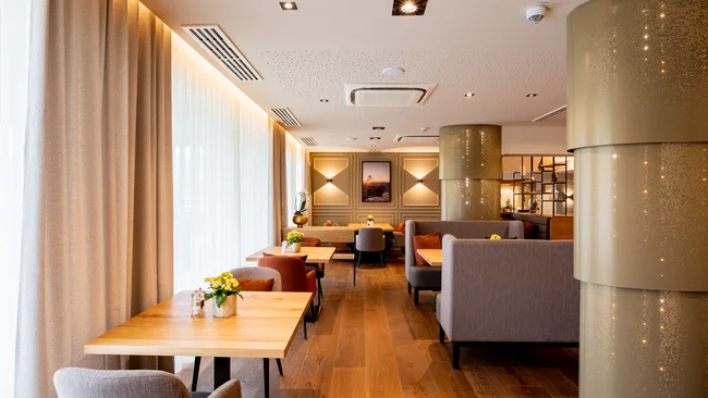 Modernes Café mit Holztischen, bequemen Stühlen und warmem Licht