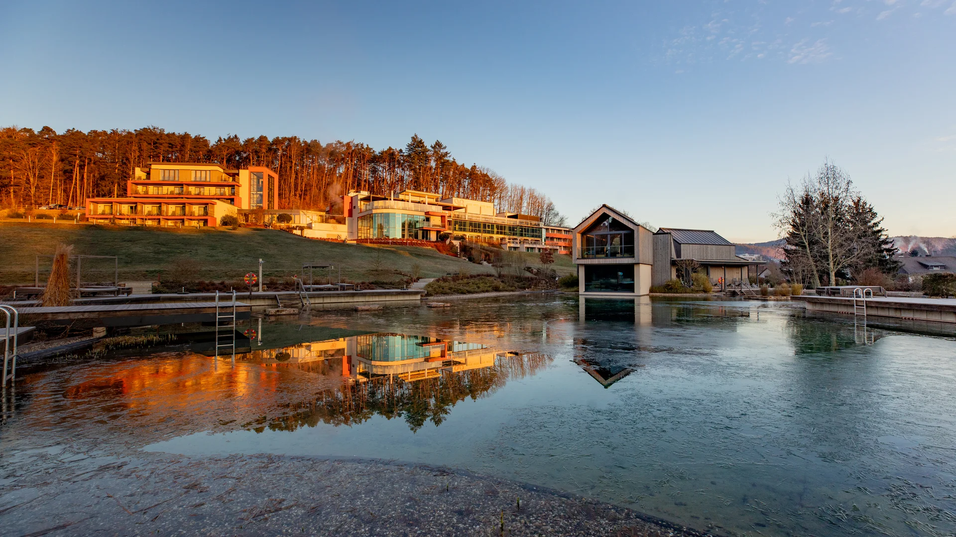 Modern buildings by a lake with forest in evening light