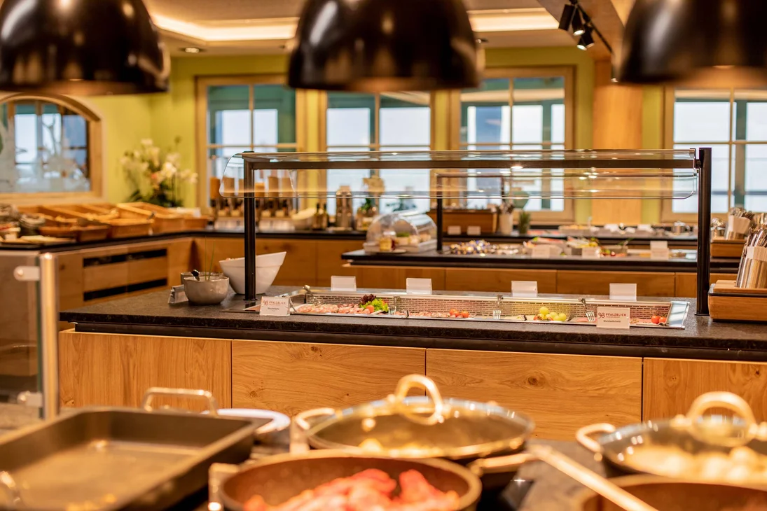 Buffet mit verschiedenen Speisen und Kochutensilien in einem gut beleuchteten Raum